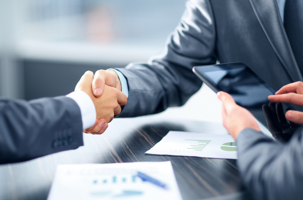 two men shaking hands in a real estate business meeting