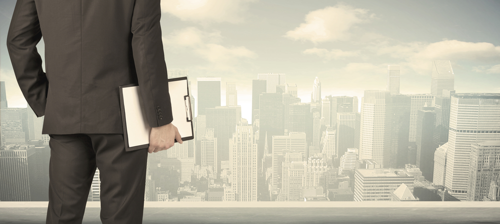 Man with clipboard looking over city